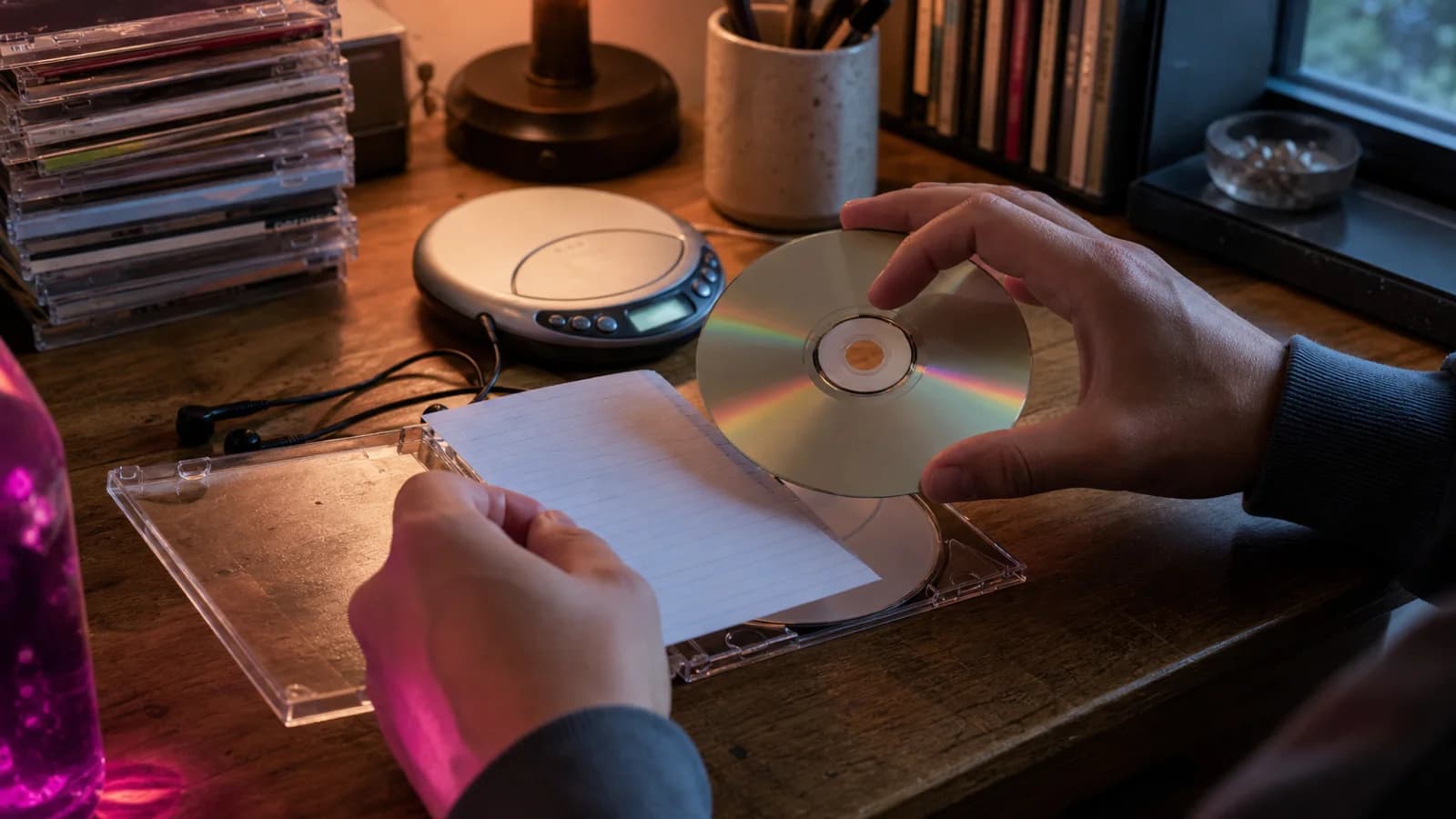 ポータブル CD プレイヤーの横で透明ケースに CD を入れる手元