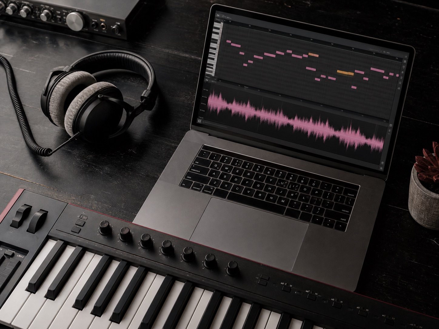 MIDI keyboard beside a laptop showing an audio waveform and piano roll